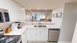 Una cocina moderna con armarios blancos, un lavamanos doble, un lavavajillas integrado y una estufa.