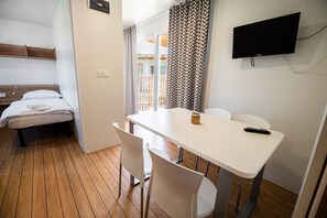 Cozy retreat with a single bed, wooden headboard, and a compact dining area.