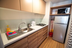 Compact kitchen with a gas stove, stainless steel sink, and refrigerator.
