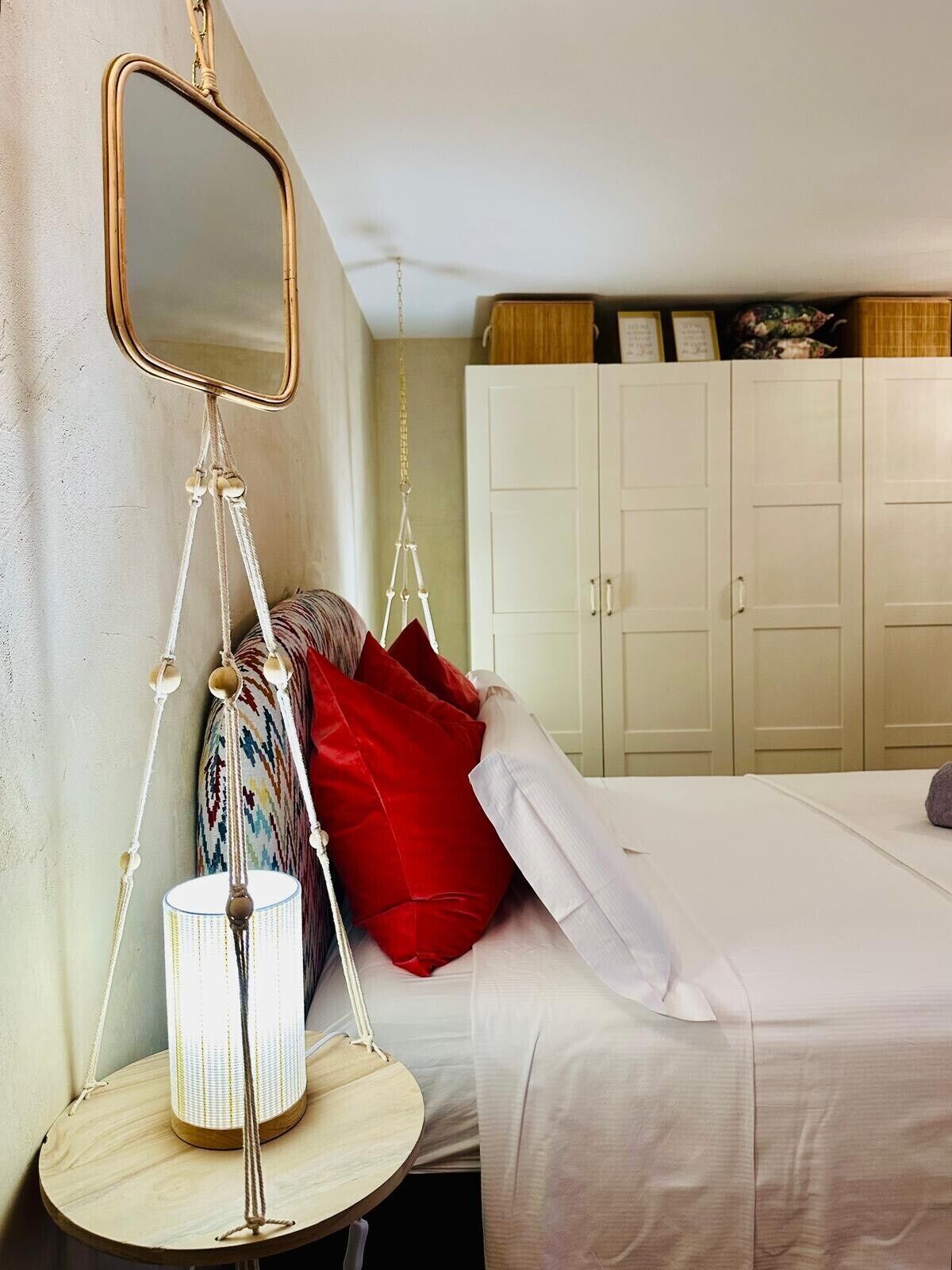 A bedroom with a hanging chair, a bedside lamp, a mirror, and a wardrobe.