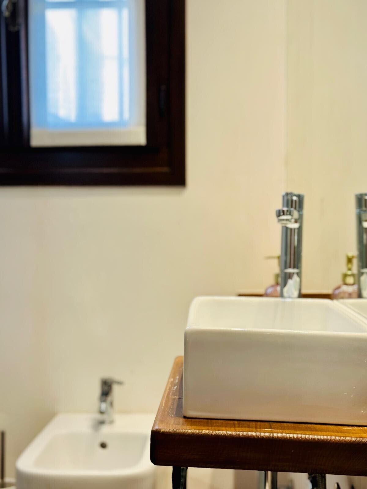 Un baño con un lavamanos blanco, un espejo y un cuadro enmarcado en la pared.