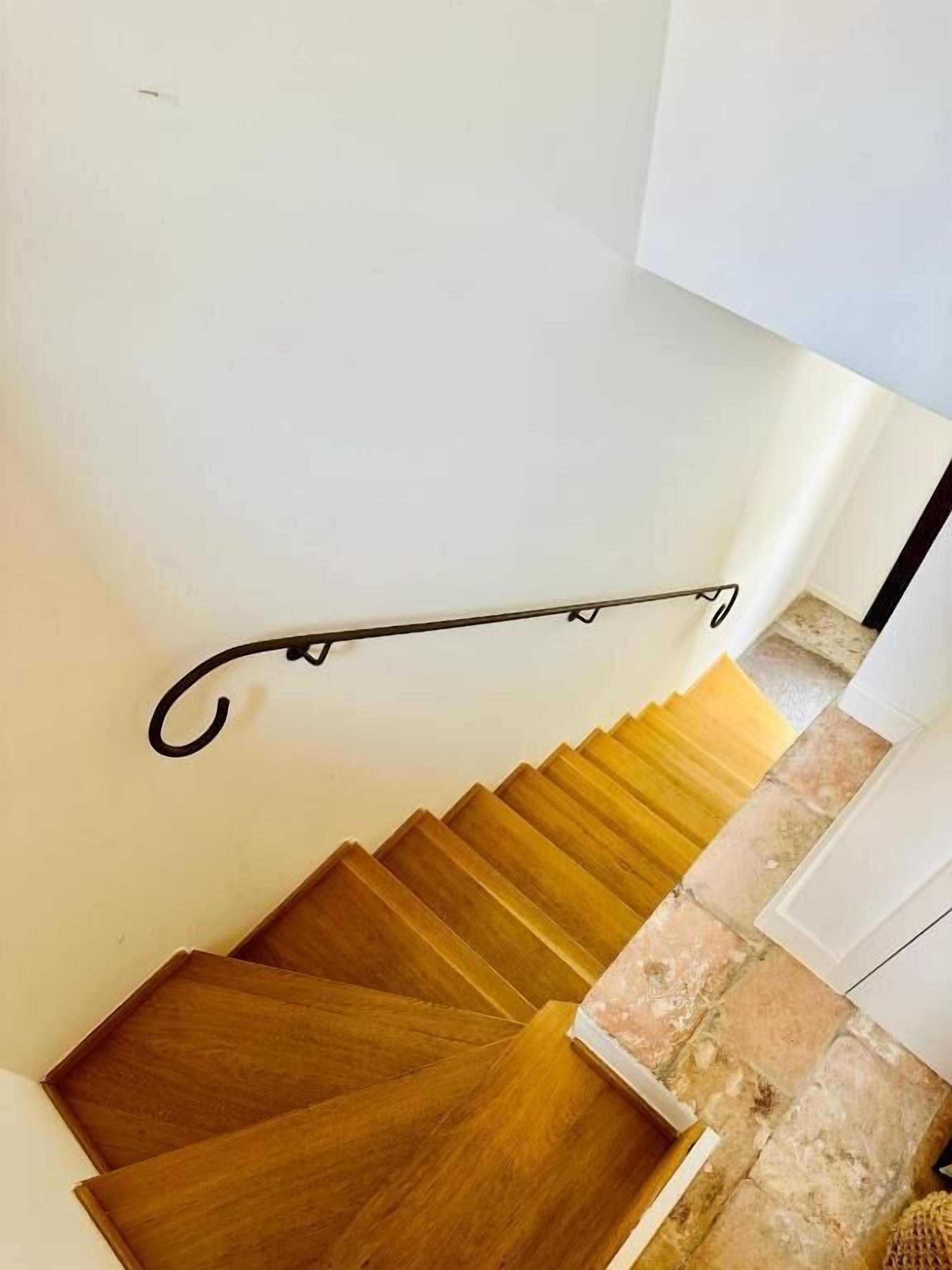 Una escalera de madera con barandilla metálica.