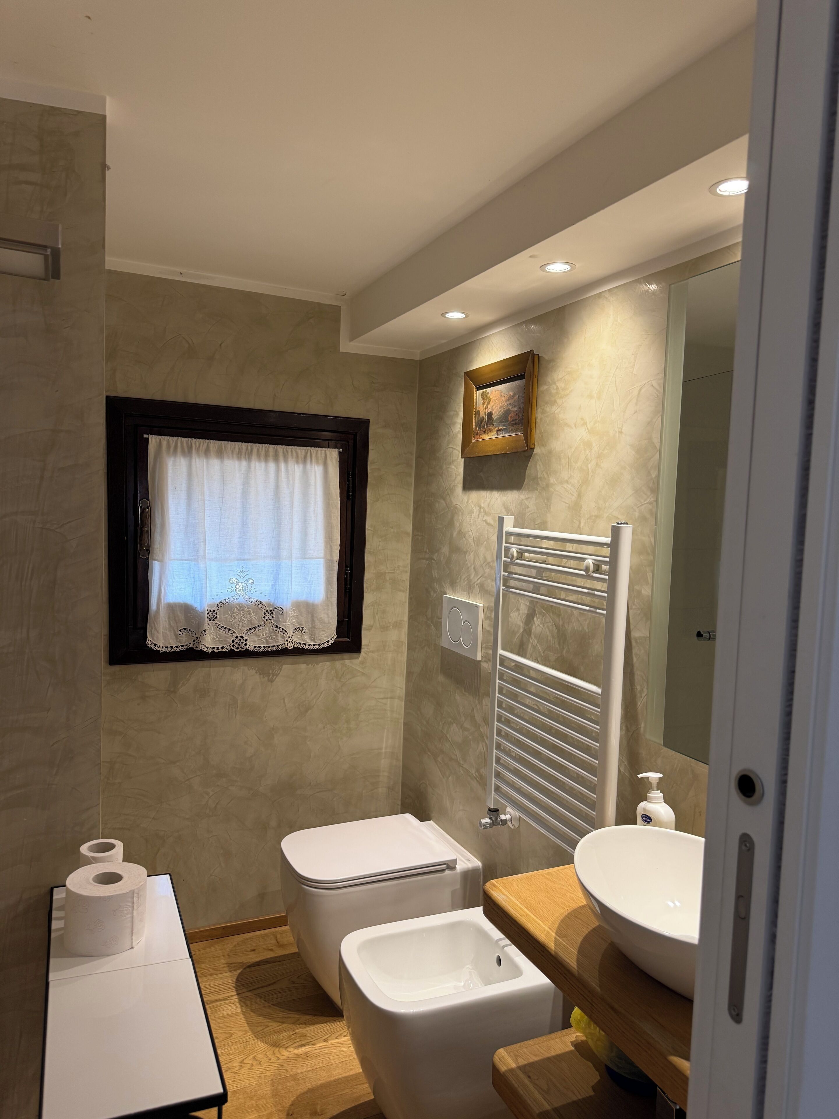 Un baño con inodoro, bidé, lavabo y un perchero para toallas.
