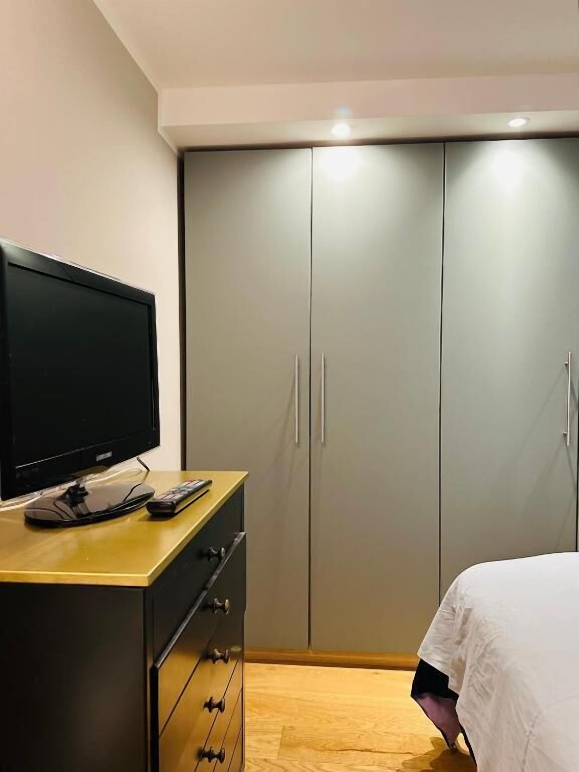 A bedroom with a bed, a TV on a dresser, and a wardrobe.