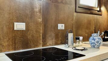 Una cocina moderna con placa de inducción negra, horno de acero inoxidable y encimera de madera.