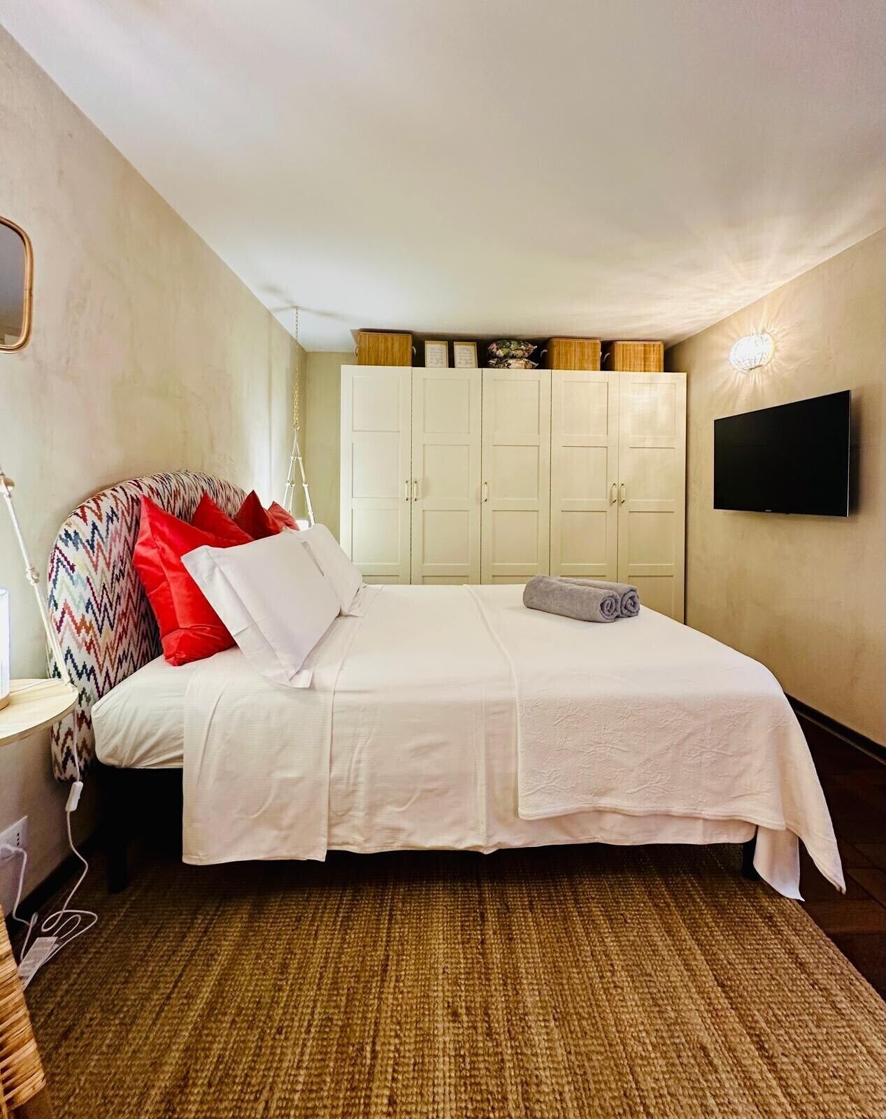 Un dormitorio con una cama, televisor y armario.