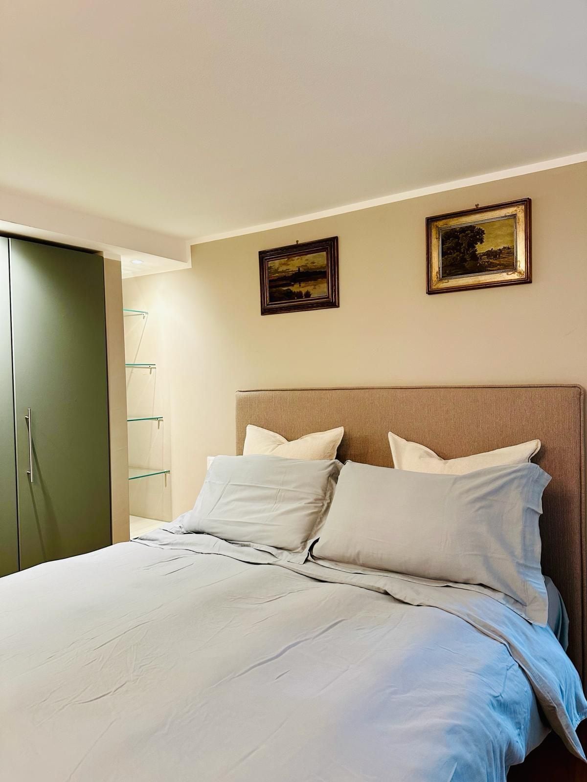 Une chambre à coucher avec un lit, une armoire et deux tableaux encadrés accrochés au mur.