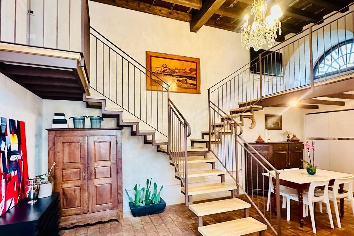Ein rustikales Interieur mit einer Holztreppe, einem Essbereich und einem großen Gemälde an der Wand.
