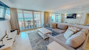 A modern living room with a sofa, coffee table, and a TV on the wall. - Shoreline Towers 1052 - Beautiful 2 BR with Gulf views (Destin)