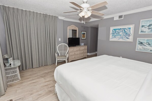 A hotel room with a bed, a television on a dresser, a chair, and artwork on the wall. - Shoreline Towers 1084 - Beautiful 2 BR with Gulf views and on the beach (Destin)