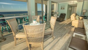 Un balcone con tavolo in vetro, sedie e vista sull'oceano.