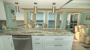 Una cucina con un'isola grande, mobili bianchi e vista sull'oceano.