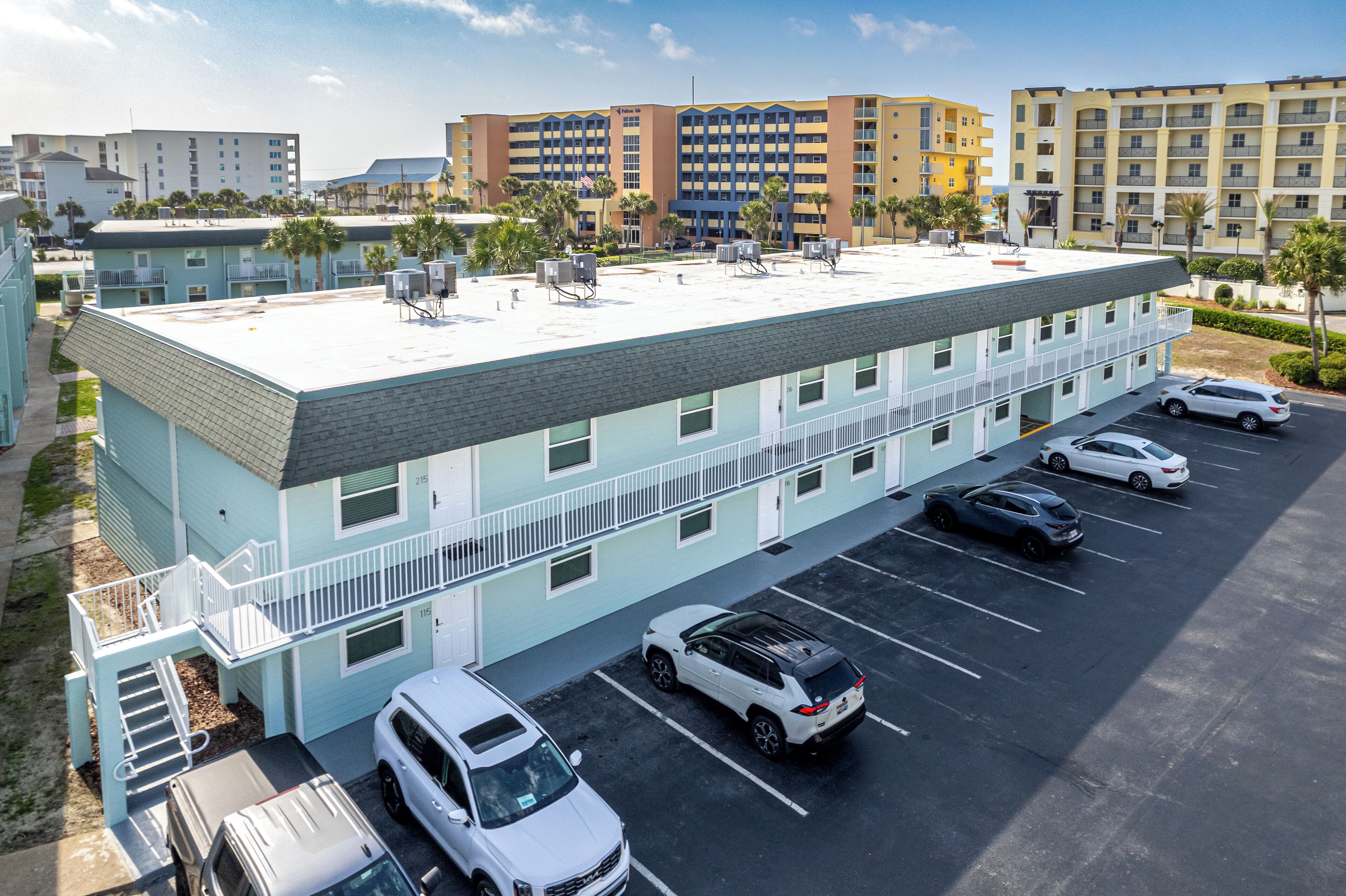 Un hôtel à plusieurs étages doté d’un parking sur le toit, où plusieurs voitures sont garées, et qui offre une vue dégagée sur les bâtiments environnants.