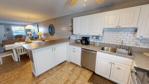 Una cocina moderna con muebles blancos, encimera de granito y lavavajillas integrado.