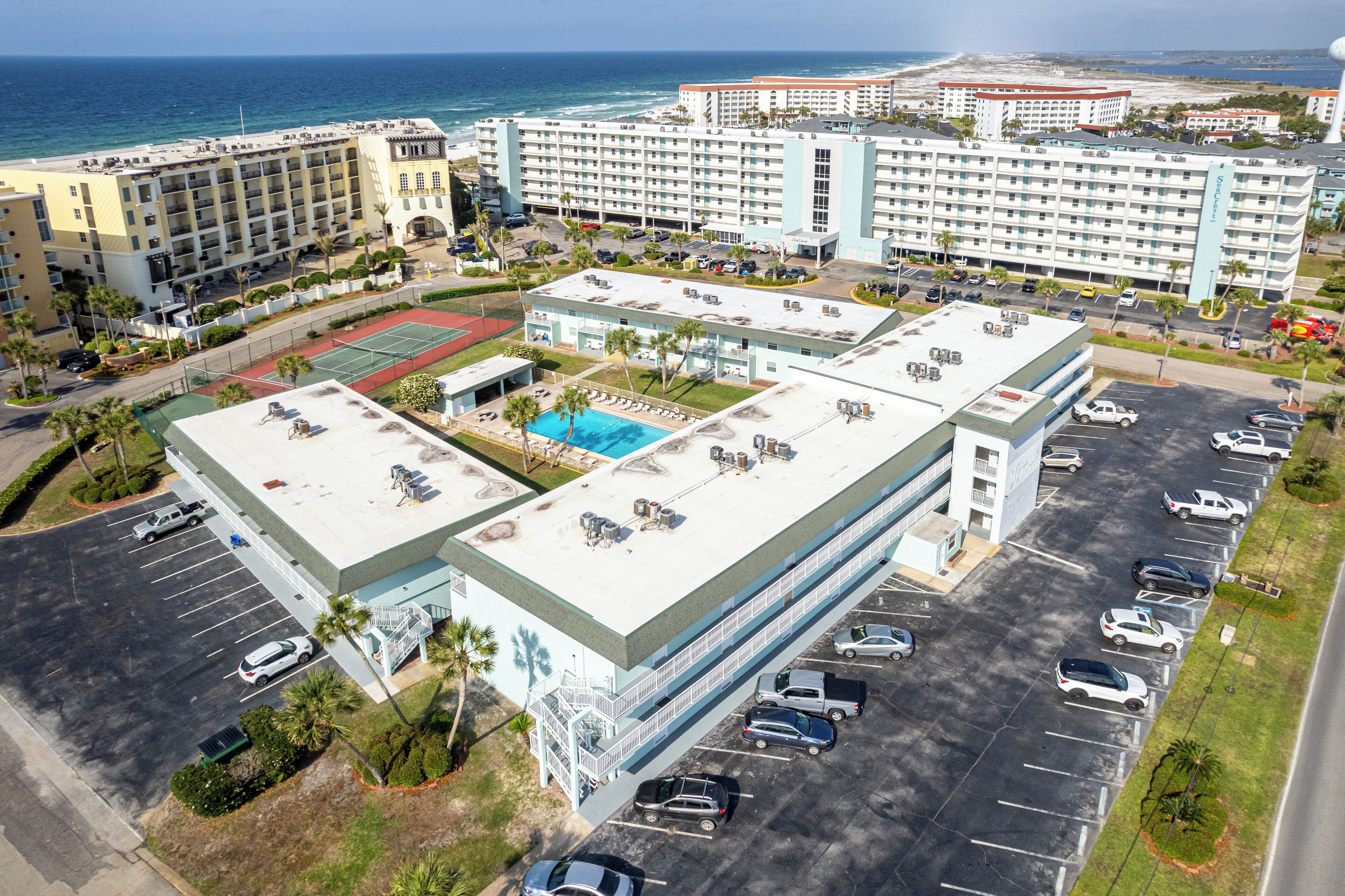 Vista aèria d'un hotel amb diversos edificis, un aparcament i una zona de piscina.