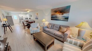 A living room with a sofa, armchairs, a coffee table, and a dining area with a table and chairs. - Venus 308 overlooking pool Easy Beach Access (Fort Walton Beach)