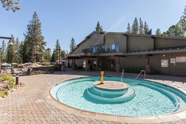 A pool area with a circular design, a building with a flat roof and large windows, and a surrounding landscape with trees. - Family Getaway | King Bed | Rec Center Access | Near Village, Trails & Lake (Truckee)
