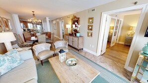 A spacious living room with a dining area, a large mirror, and a kitchen visible through an open door. - Destin on the Gulf 603 is a Stunning Gulf Front 2 BR.  Enjoy Free Beach Service (Destin)