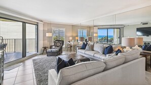 A spacious living room with a large sofa, a dining area, and a balcony with a view of the ocean. - IR 315 Beautiful 2 bedroom/2 bath (Destin)