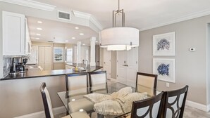 A modern kitchen with white cabinets, a glass dining table, and a pendant light. - IR 315 Beautiful 2 bedroom/2 bath (Destin)