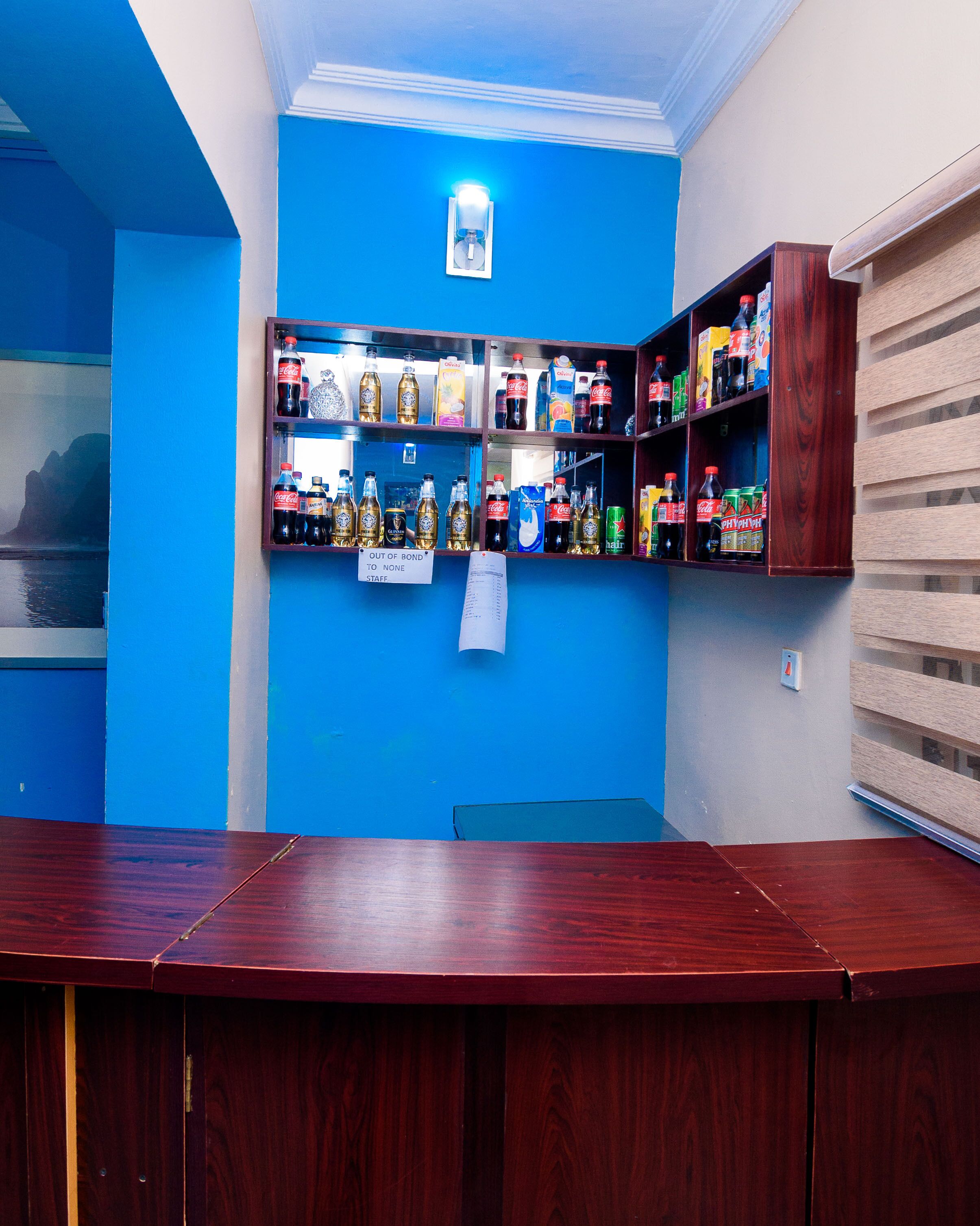 A bar area with shelves stocked with various beverages, a counter, and a blue wall.