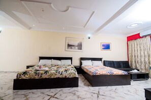 A hotel room with two beds, a marble floor, a ceiling with recessed lighting, and a red accent wall. - D'Tavern Apartment (Ibadan)