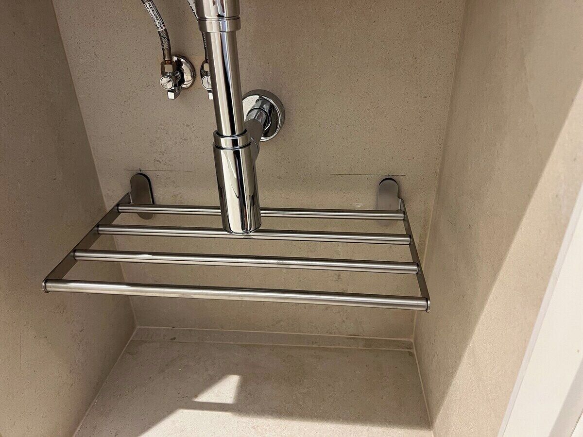 Een douchegedeelte met een chromen plank en een kraan.