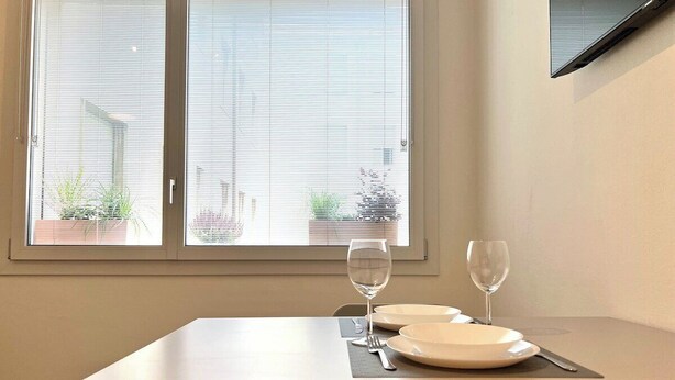 Une table à manger avec deux assiettes et deux verres à vin, dressée pour deux personnes.