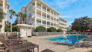 A multi-story hotel with a swimming pool, outdoor seating, and a covered area.