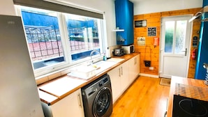 A compact kitchen with a washing machine, a microwave, and a sink.