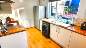 A compact kitchen with a washing machine, a toaster, and a window with a view of the outside.