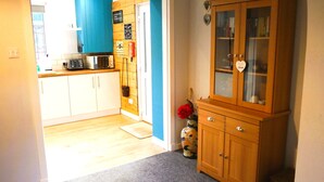 A kitchen with white cabinets, a microwave, and a toaster. There's a wooden cabinet with glass doors and a vase with flowers.