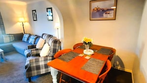 A dining area with a wooden table, chairs, and a vase with flowers.