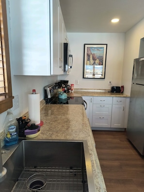 A kitchen with white cabinets, a stainless steel sink, a toaster, and a refrigerator.