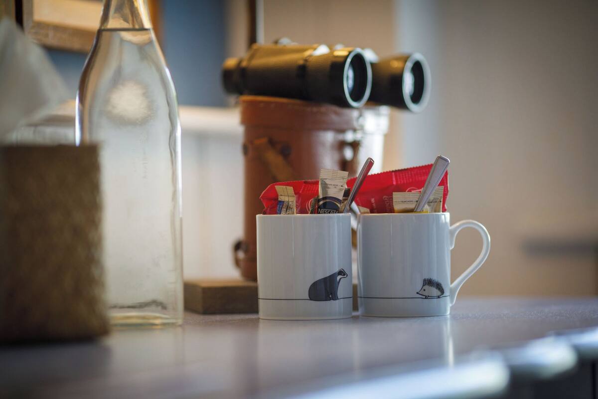 Two white mugs with animal designs, a clear bottle, and a red bag with a straw.