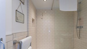 A modern bathroom with white tiled walls, a glass shower enclosure, and a towel rack. - The Boathouse (Bath)