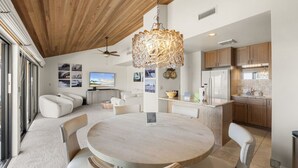 Una cocina moderna con armarios de madera, una isla central y un comedor con una mesa redonda y sillas.