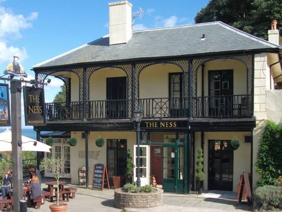 A building with a sign reading "The Ness" and outdoor seating.
