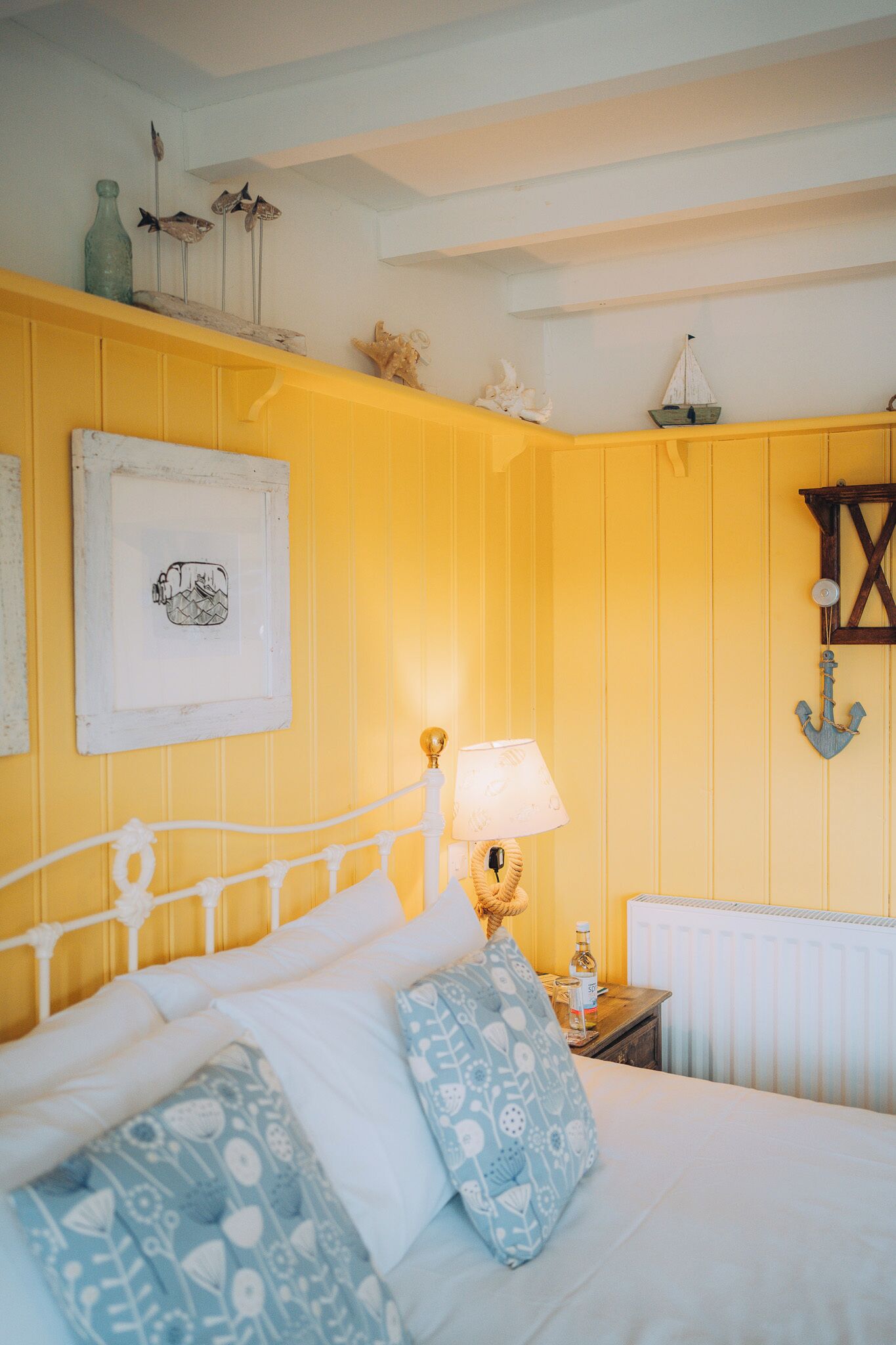 A bedroom with a bed, a nightstand, a lamp, and nautical decor.