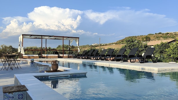 A pool with lounge chairs and a pergola, surrounded by a tiled patio and a view of the countryside. - AgriBarocco (Noto)