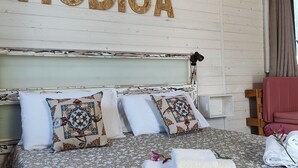 A bed with floral bedding, a headboard with 'MODICA' written on it, and a wall-mounted air conditioner. - AgriBarocco (Noto)