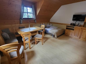 A cozy room with a wooden table, chairs, a bed, and a TV.