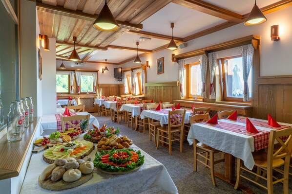 A dining area with tables set for a meal, featuring a variety of food items on platters.