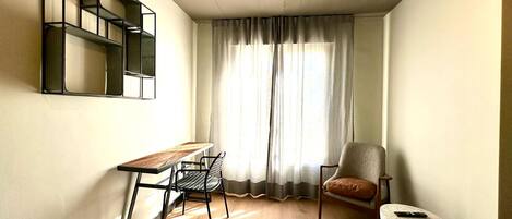 Una habitación pequeña con escritorio, silla y un taburete.