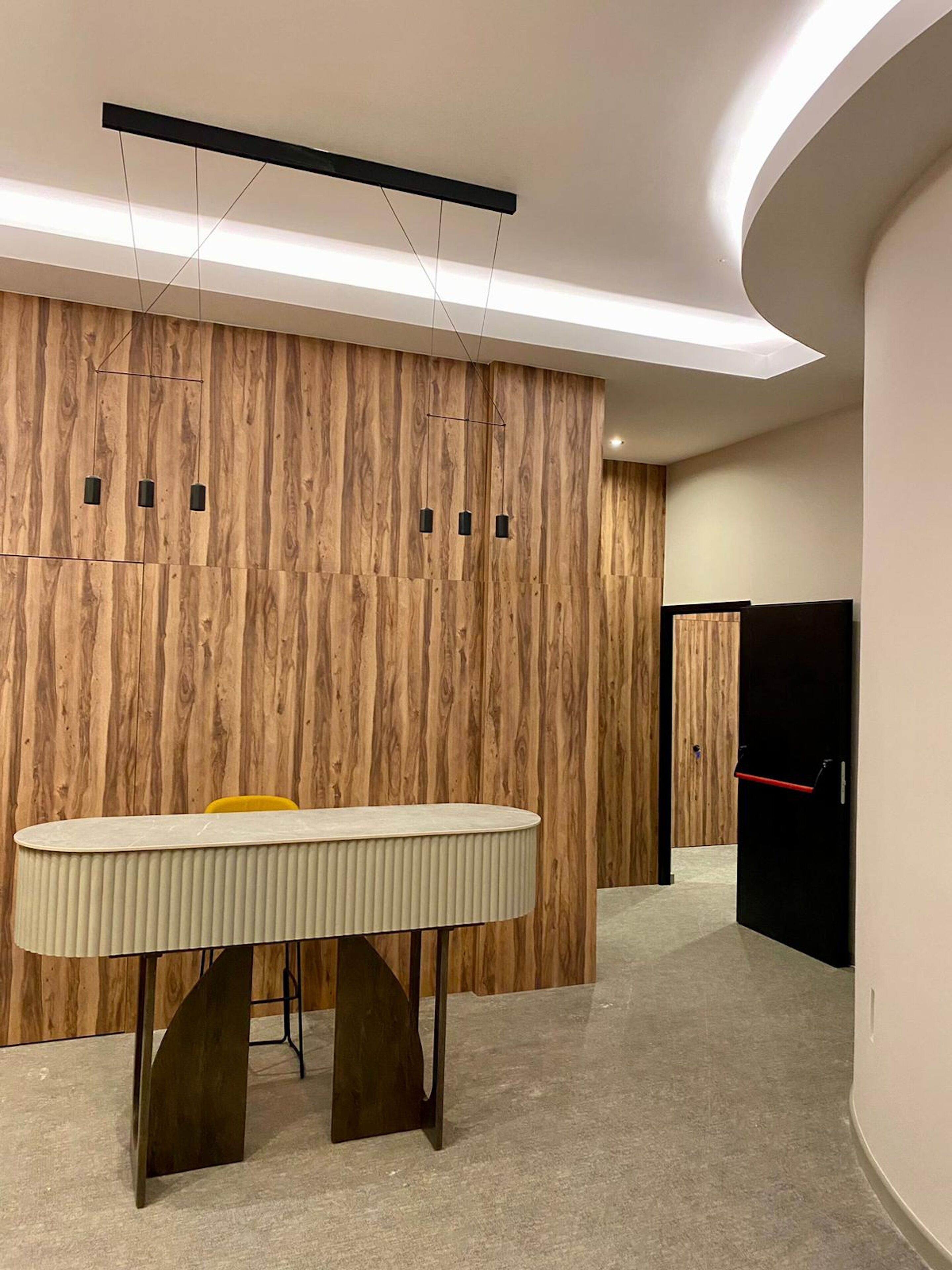 Un intérieur moderne avec un mur lambrissé en bois, une table centrale au design original et un mur incurvé.