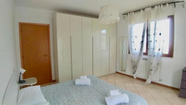 A bedroom with a bed, a wardrobe, a desk with a lamp, and a window with curtains. - CLEO CAMELIA (Falconara Marittima)