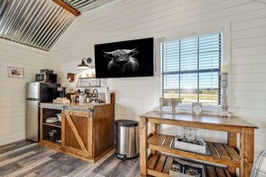 A kitchen with a wooden island, stainless steel appliances, and a large window with blinds. - Holy Cow Cottage w/Amazing Hill Country Views (Fredericksburg)