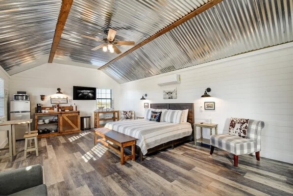 A spacious room with a high ceiling, a bed, a desk, a chair, and a sofa.