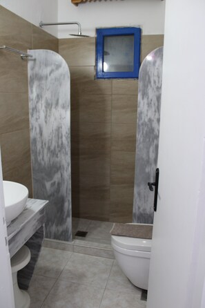 A bathroom with a shower, toilet, and sink. - The Three Anchors Rooms (Santorini)