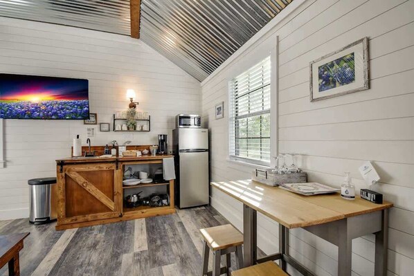 Cocina compacta con una isla de madera, un refrigerador y una ventana con persianas.